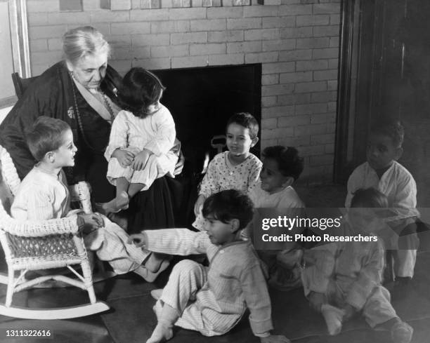 American settlement movement activist and social reformer Jane Addams sits with children at Hull House , Chicago, Illinois, circa 1930.