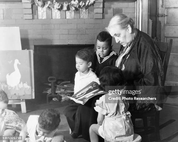 American settlement movement activist and social reformer Jane Addams reads to children at Hull House , Chicago, Illinois, circa 1930.