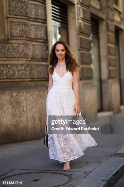 Ophélie Duvillard wears a white long pleated lace mesh summer dress with floral embroidery from Maje, a blue and beige basket large bag made of straw...