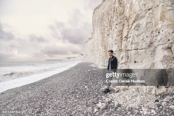 English pop singer and musician Tom Chaplin pictured on the pebble beach at Birling Gap, near the resort town of Eastbourne during a photo shoot to...