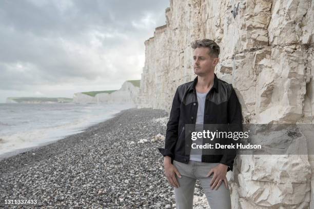 English pop singer and musician Tom Chaplin pictured on the pebble beach at Birling Gap, near the resort town of Eastbourne during a photo shoot to...