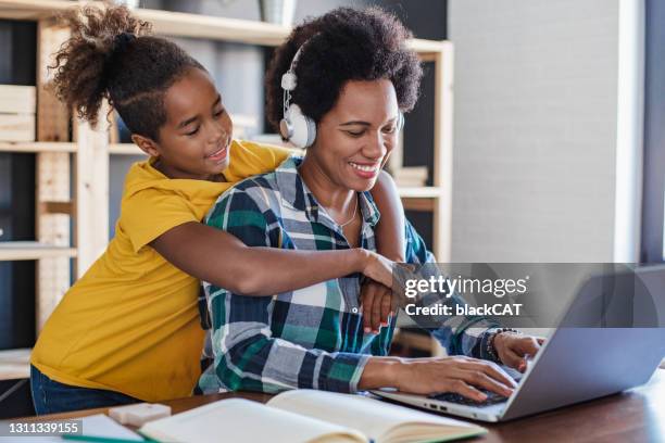 employed mother working from home and her daughter embracing her at home - dominican ethnicity stock pictures, royalty-free photos & images