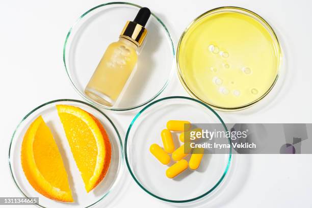 beauty concept of vitamin c serum in cosmetic bottle with dropper and slices of orange fruit. - vitamin c stock-fotos und bilder