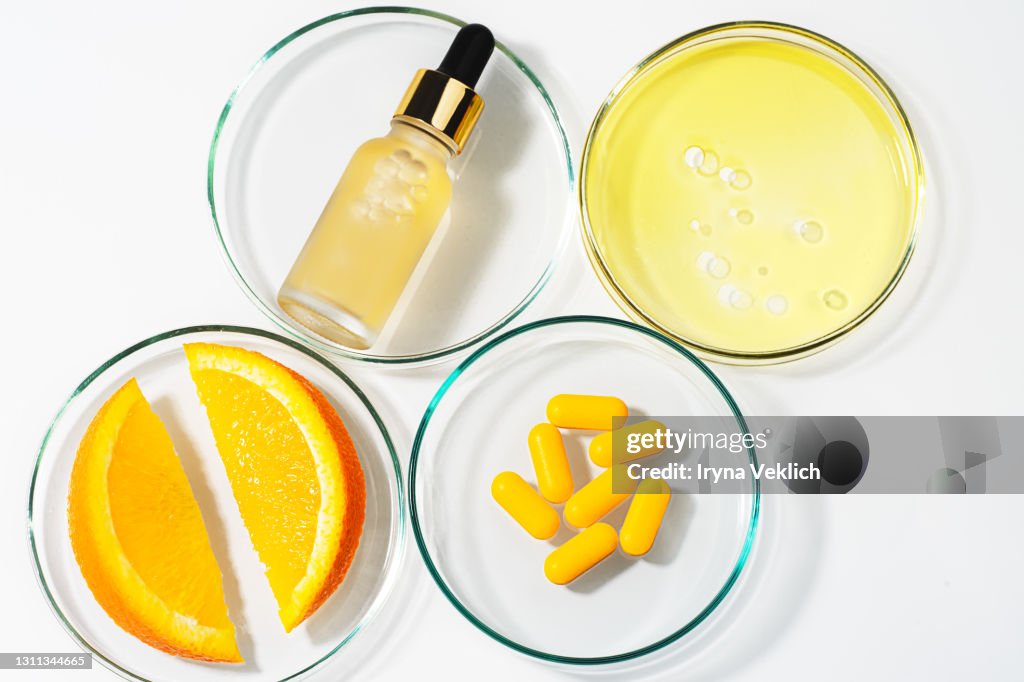 Beauty concept of Vitamin C serum in cosmetic bottle with dropper and slices of orange fruit.