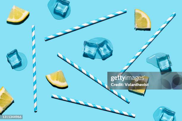 melting ice cubes, lemon slices and drinking paper straw on blue background - straw stock-fotos und bilder