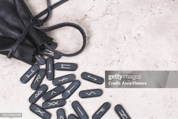 stone runes and leather pouch on concrete gray background. concept of magic esoteric rituals. top table view and extreme close-up - runes stock pictures, royalty-free photos & images