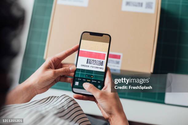 nicht erkennbare online-shop-besitzer beim scannen eines qr-codes auf einem paket mit ihrem mobiltelefon - strichkodeleser stock-fotos und bilder