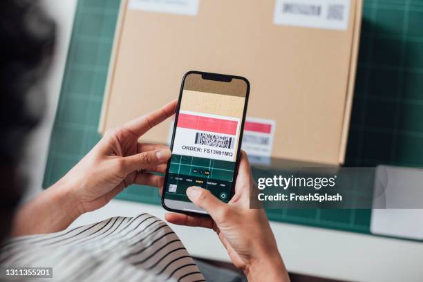 onherkenbare online winkeleigenaar die een qr-code scant op een pakket met haar mobiele telefoon - impression stockfoto's en -beelden