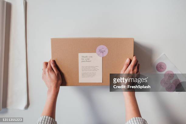 anonimo piccolo imprenditore online in possesso di un pacco pronto per la consegna - contenitore foto e immagini stock