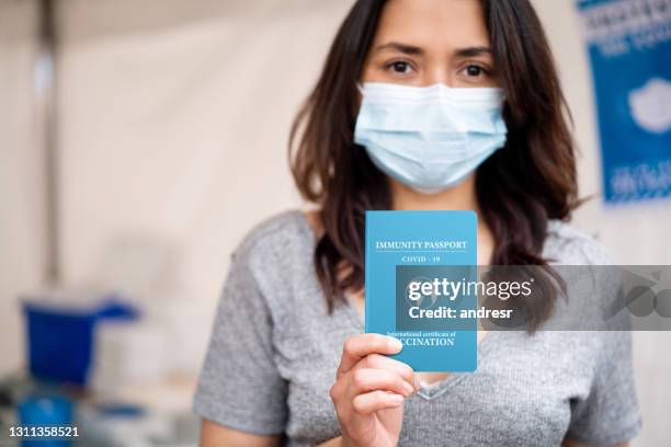 jeune femme retenant un passeport d’immunité covid-19 - passeport vaccinal photos et images de collection