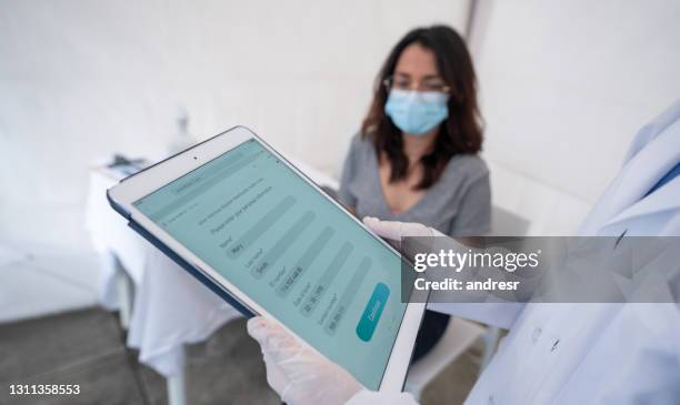 woman being registered for her covid-19 vaccine at an immunization stand - registration form stock pictures, royalty-free photos & images