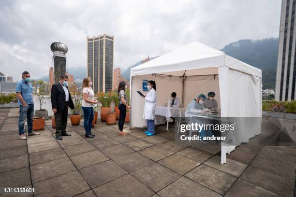 people in line waiting to get their covid-19 vaccine at a stand - medical tent stock pictures, royalty-free photos & images