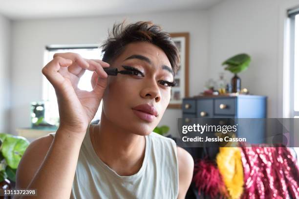 man applying drag queen makeup at home - mascara stockfoto's en -beelden