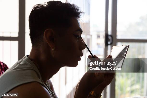man applying drag queen makeup at home - travesti imagens e fotografias de stock