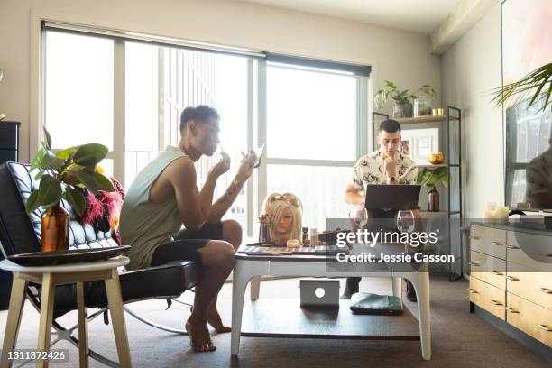 man applying drag queen makeup at home while partner uses laptop - auckland covid stock pictures, royalty-free photos & images