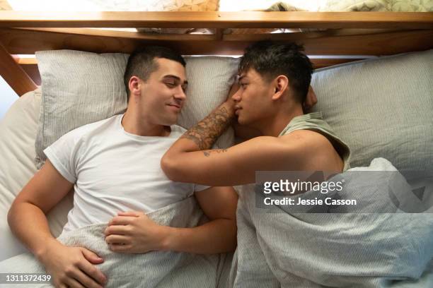 a gay couple sleep in their bed - men in bed stock-fotos und bilder