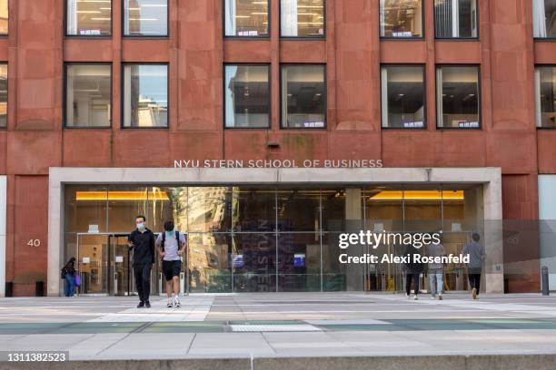 Students wearing masks walk out of the NYU Stern School of Business amid the coronavirus pandemic on April 07, 2021 in New York City. After...