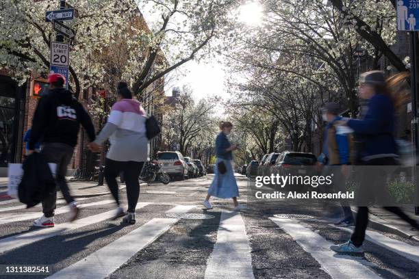 People move past Japanese Cherry Blossom trees lining a street in the West Village amid the coronavirus pandemic on April 07, 2021 in New York City....