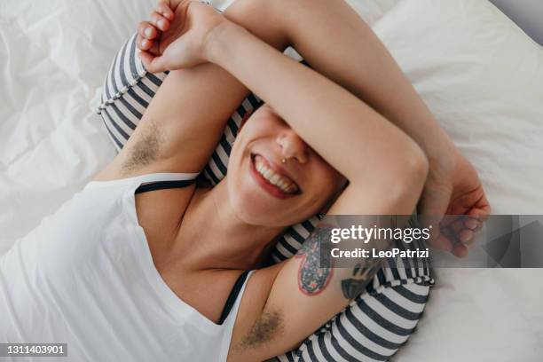 young woman relaxing on the bed - female hairy arms stock pictures, royalty-free photos & images