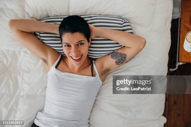 young woman relaxing on the bed - armpit hair woman stock pictures, royalty-free photos & images