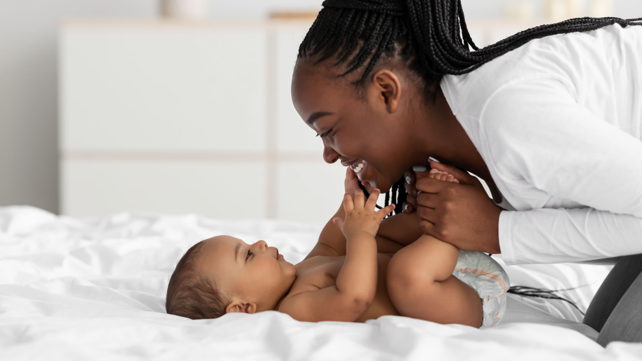 African American mom playing in bed with her black baby African American mom playing in bed with her black baby