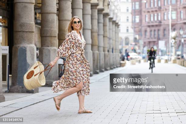 German actress Lara-Isabelle Rentinck wearing sunglasses by Chloe, a long multicolored maxi dress with floral print by Tory Burch, a dark brown and...