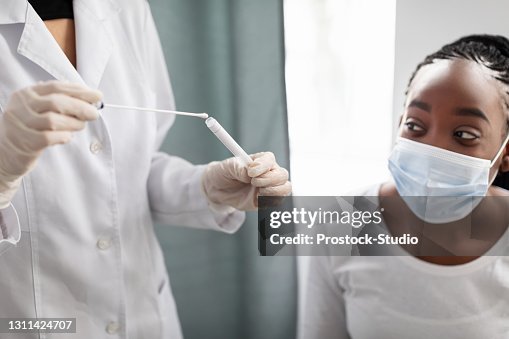 Doctor taking PCR test sample from potentially infected afro lady Doctor taking PCR test sample from potentially infected afro lady
