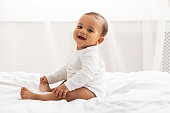 Portrait Of African Baby Toddler Smiling Sitting On Bed Indoor
