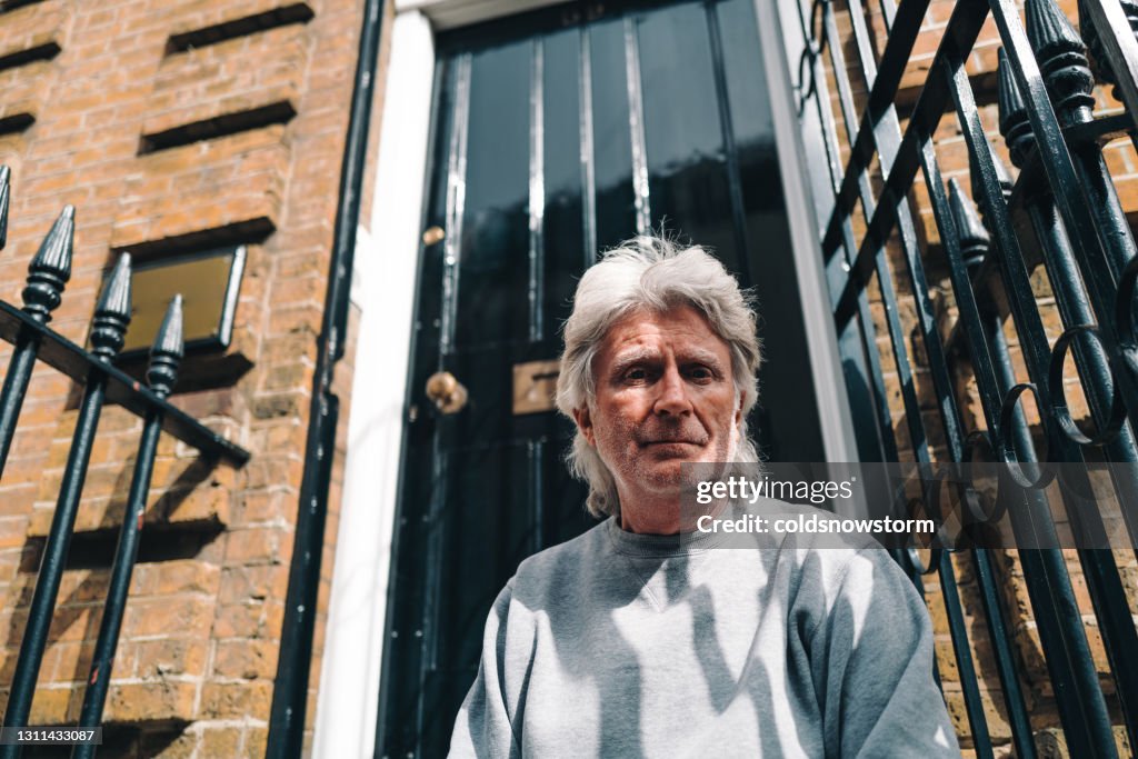 Homeless senior man sitting on steps on city street