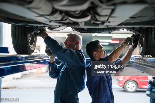 mecánicos de coches revisando el chasis del vehículo - car mechanic fotografías e imágenes de stock