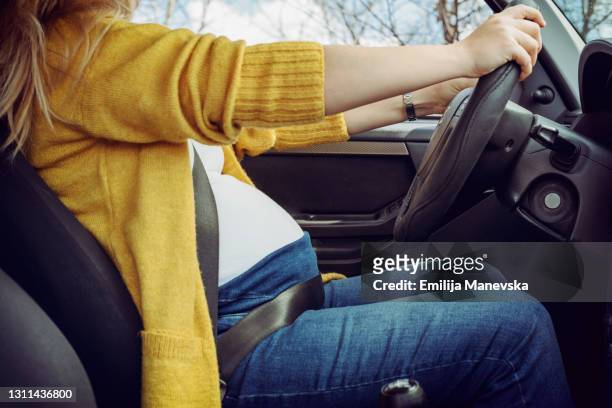 pregnant woman fastening safety belt in car - pregnant woman car stock pictures, royalty-free photos & images