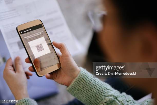 mujer adulta mediana escaneando código qr con teléfono inteligente - barcode scanner fotografías e imágenes de stock