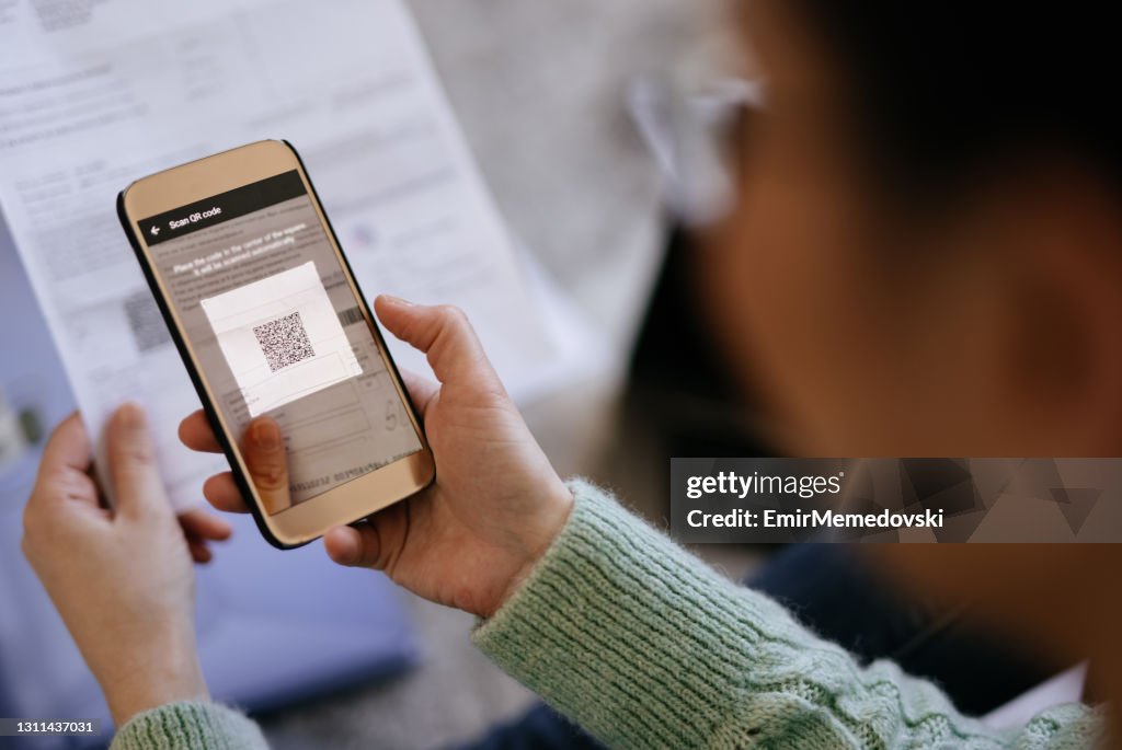 Mid adult woman scanning QR code with smart phone