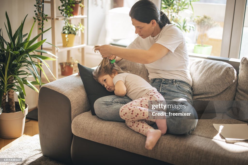 Mother doing head lice cleaning on daughter