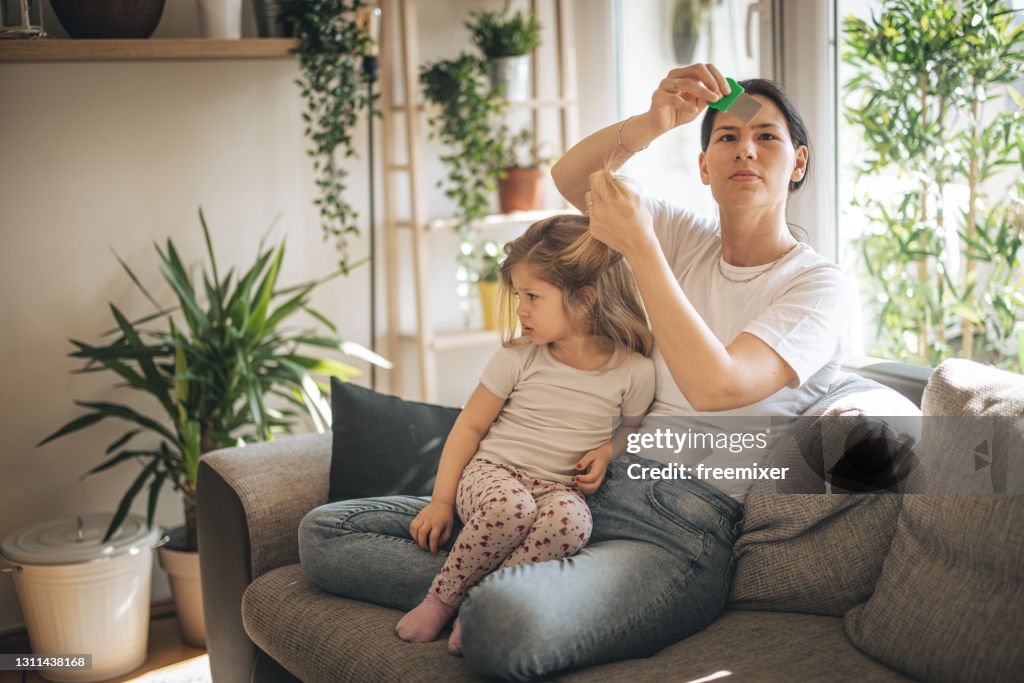 Mother doing head lice cleaning on daughter