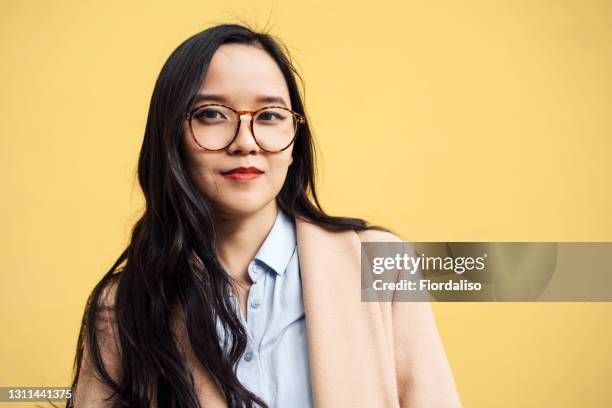 young asian womanwith glasses - portrait coloured background stock pictures, royalty-free photos & images