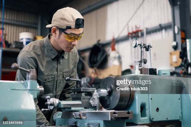 mâle adulte moyen utilisant un garçon pour la machine un morceau de métal - metal workshop photos et images de collection