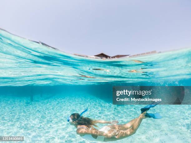 de vrouw duikt in tropisch overzees, gespleten schermafbeelding onderwaterschot, overwatervilla's op achtergrond - under water stockfoto's en -beelden