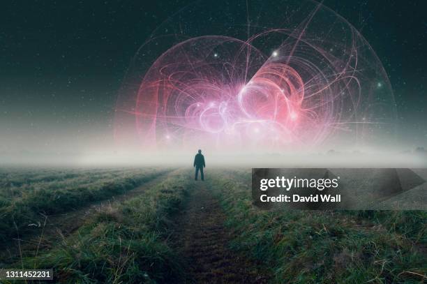 a man standing in a  misty atmospheric field at night looking up at an alien science fiction structure in the sky. - space travel vehicle stockfoto's en -beelden