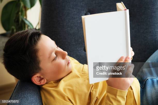 8 jahre altes kind lesebuch zu hause. sitzen auf dem sofa. er macht digitale entgiftung - 8 9 years stock-fotos und bilder