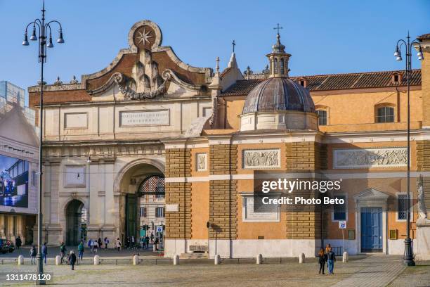 the ancient roman gate of piazza del popolo in the heart of rome with the side facade of the church of santa maria - piazza del popolo rome stock pictures, royalty-free photos & images