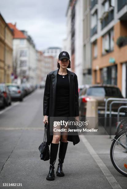 Celine Bethmann wearing black New Era cap, black Zara coat, Tiffany & Co silver chain, black Mango mini dress, black YSL bag and H&M leather boots on...