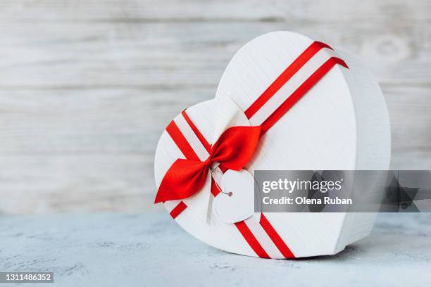 white heart shape box with satin red-white ribbon and bow on white background - heart box ribbon stockfoto's en -beelden