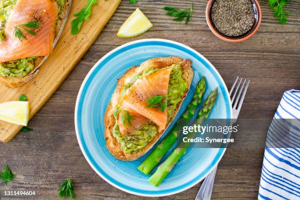 avocado-toast mit räucherigem lachs und spargel - graved lachs stock-fotos und bilder