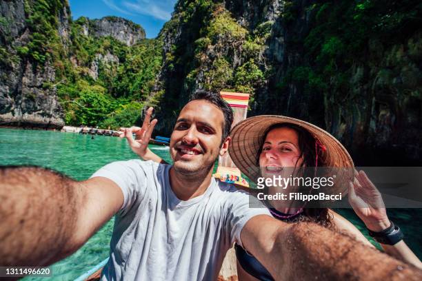 jonge paar selfie op een longtailboot in thailand, phi phi island - longtailboot stockfoto's en -beelden