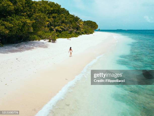 joven adulta caminando en una playa paradisíaca en maldivas - island fotografías e imágenes de stock