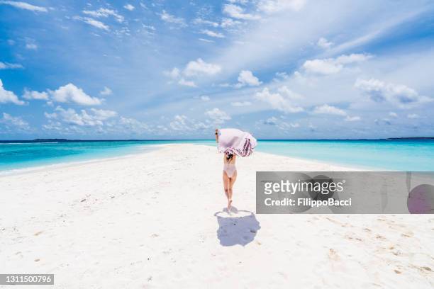 jonge volwassen vrouw die van een paradijselijk strand in malediven geniet - strandhanddoek stockfoto's en -beelden