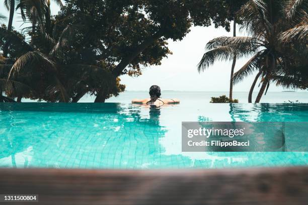 jonge volwassen vrouw die in een zwembad ontspant - bikini atoll stockfoto's en -beelden