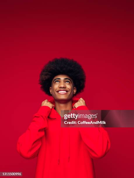 homme afro-américain avec la coiffure africaine restant au-dessus du fond rouge d’isolement - mode et couleur photos et images de collection
