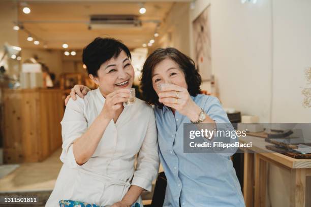 two mature ladies drinking tea together - taipei tea stock pictures, royalty-free photos & images